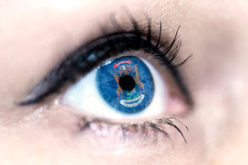 Flag of Michigan state of the United States of America reflects in a woman blue eye - election, sport, hope, young, generation, american football, basket, emotion