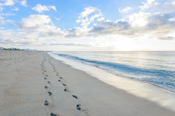 Fantastic ocean beach view with small figures of people and foot prints on sand. Cabo San Lucas. Mexico.