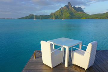Table and chairs with a view of the Mont Otemanu and the Bora Bora lagoon in French Polynesia - obrazy, fototapety, plakaty