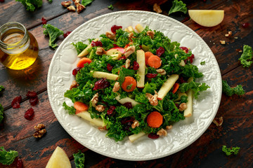 Kale salad with dried cranberry, carrots, walnuts and apple. healthy vegan food.