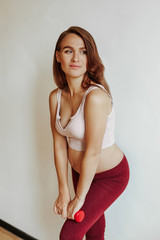 Beautiful pregnant woman during sports. Raise the weight with your hand.