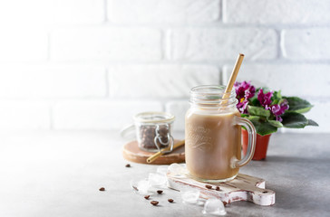 Ice coffee with milk and ice in a glass jar on a light background. Bamboo drinking straws with Zero - waste. Glass mason jar.