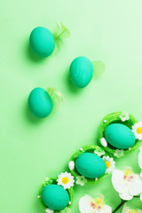 Colored easter eggs with feathers on a green background. Monochrome. Top view.