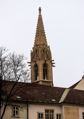 Fototapeta na wymiar Torre de una catedral de Bratislava detrás de un techo de un edificio antiguo