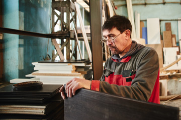 Process of production and manufacture of wooden furniture in furniture factory. Worker carpenter...