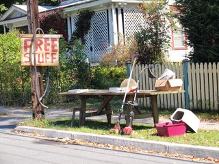 A Free Stuff sign with yard sale leftovers by the curb