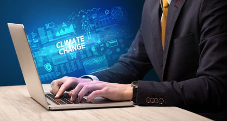 Businessman working on laptop with CLIMATE CHANGE inscription, cyber technology concept