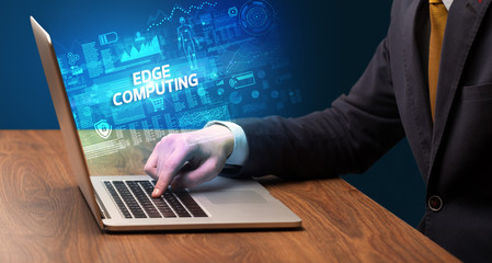 Businessman working on laptop with EDGE COMPUTING inscription, cyber technology concept