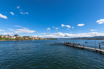 Fototapeta na wymiar Panorama view of the Zurichsee (Zurich lake) and the cityscape of old town with Swiss Alps mountain range and blue sky cloud in background on a sunny summer day, Zurich, Switzerland