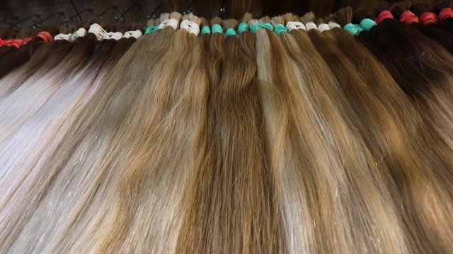 Long hair extensions in the salon close-up. Natural female hair, beautiful female hair.