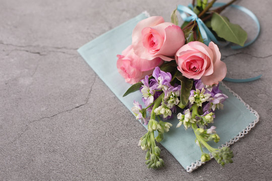 Bouquet of Pink Roses and Purple Stock tied with a Purple Ribbon on a Blue Napkin