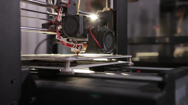3D technology the printer head prints a plastic part light in background close up