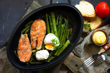 Green asparagus, grilled salmon and poached eggs. Healthy food on rustic wooden background. Top view flat lay background. Copy space.