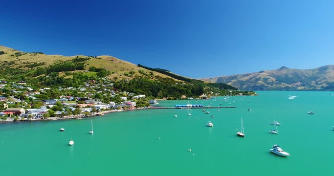 Aerial 4k backward tracking motion view of the boat harbour and waterfront at the historic township of Akaroa in the Canterbury shire on South Island,New Zealand