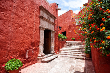 Fototapeta premium Narrow street with the arch of the monastery of Santa Catalina, Arequipa, Peru, potted flowers around