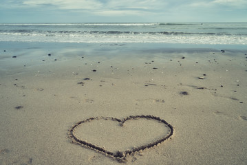 Obraz na płótnie Canvas Schriftzug Herz in den Sand geschrieben, mit einer Muschel, dem Meer und Horizont im Hintergrund, Urlaubsgrüße