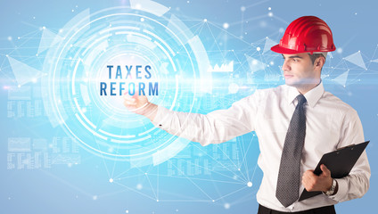 Handsome businessman with helmet drawing TAXES REFORM inscription, contruction business concept