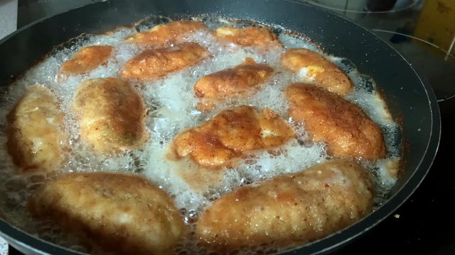 Frying chicken devolay in a lot of oil. Preparing meat meal in boiling oil with white foam on a Teflon pan. Gold fried chicken. Unhealthy food preparation.