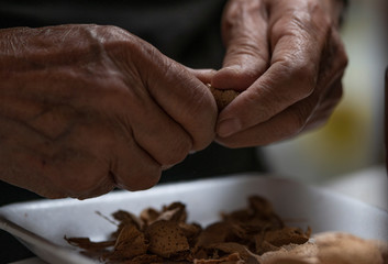 senior man's hands peeling almonds