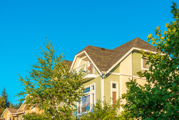 A perfect neighborhood. Houses in suburb at Summer in the north America. Top of a luxury house with nice window over blue and white sky.