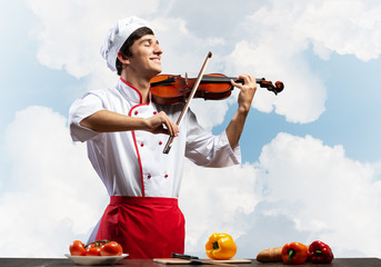 Young male chef with violin standing