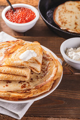 Stack of russian pancakes blini with red caviar, fresh sour cream
