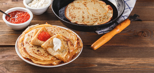 Stack of russian pancakes blini with red caviar, fresh sour cream