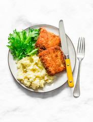 Comfort food - deep-fried fish and buttery mashed potatoes on a light background, top view