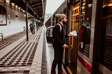 .Attractive young man with beard waiting at the train station in Vienna. Thinking about his trip,...