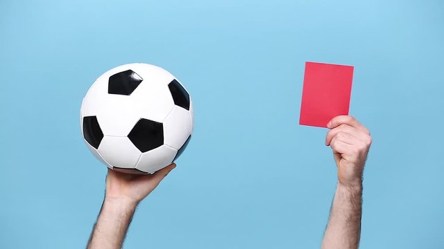 Close up cropped man football fan cheer up support favorite team with soccer ball, hands arms showing red referee judge card isolated on pastel blue background studio. People sport lifestyle concept.
