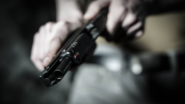 Man chambering a round in a .45 pistol. Close up with shallow depth of field.