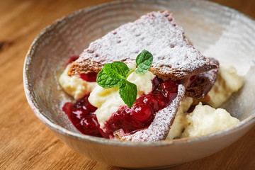 Millefeuille dessert with berry jam on a wooden table close-up