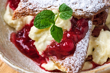 Millefeuille dessert with berry jam on a wooden table close-up