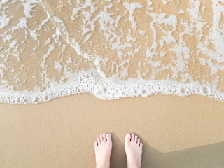 Top view little feet on sea sand and wave, Vacation on ocean beach, Summer holiday.