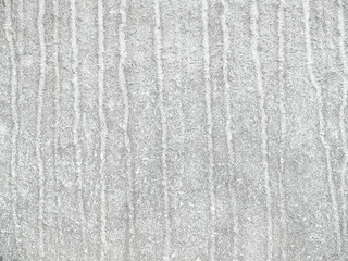 Grey-white concrete wall with many surface shapes due to condensation and splashes.