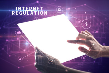 Holding futuristic tablet with INTERNET REGULATION inscription, cyber security concept