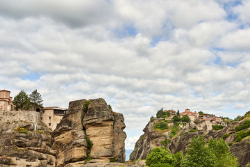 Amazing Meteora Monastery in Greece. Fantastic view at mountains and green forest against epic blue sky with clouds. UNESCO