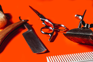 Old barber tools on an old beautiful Lush Lava surface. A razor, shaving brush, comb, hairdressers scissors, and a clipper