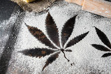 on white flour traces of cannabis leaves can be seen rusty surface near a rolling pin lies
