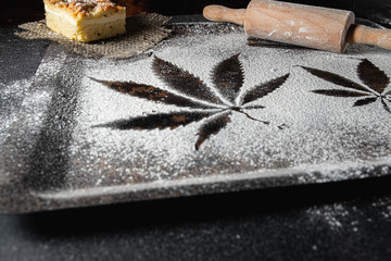 cooking cannabis food. Trail of cannabis leaf on white flour on a rust table. battledore. on a burlap treats a pie