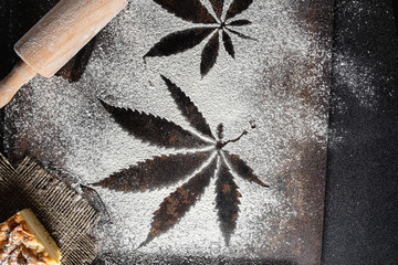 on white flour traces of cannabis leaves can be seen rusty surface near a battledore lies on a...