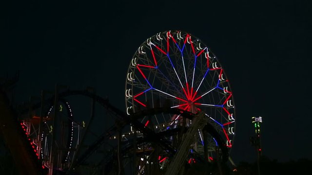 Glowing lights amusement rides in an amusement park in the evening