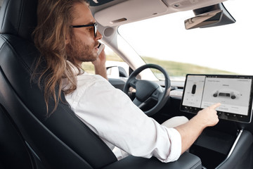 Mode of Transport. Bearded man with long hair in sunglasses traveling sitting inside electric car...