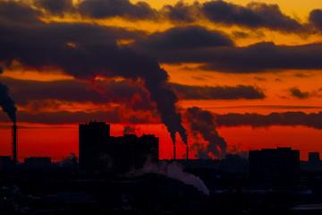 Obraz premium industrial center at sunset with chimneys and smoke