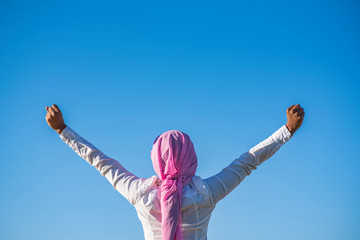 Woman with a pink headscarf raising her arms