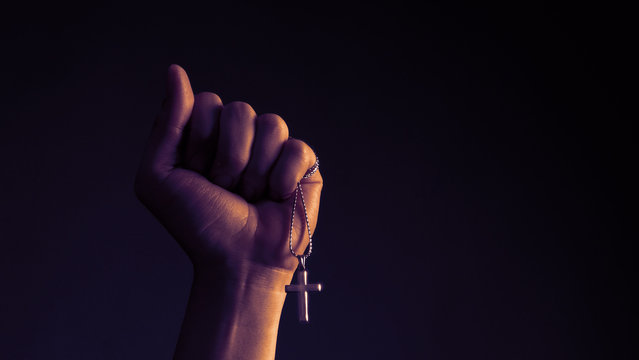 Close-up images of crucifix pendant necklace in man hand on black color background in studio which represent praying for god or jesus and thank gods for giving peaceful and faithful to people