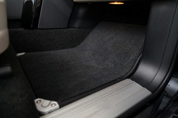 Clean car floor mats of black carpet under front passenger seat in the workshop for the detailing...