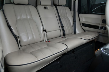 Clean after washing the rear passenger seats of white and beige genuine leather inside the interior of an expensive suv, preparation before selling the car. Auto service industry. Detailing cleaning.