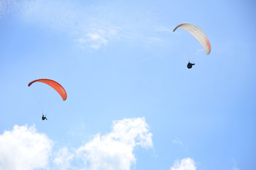 Paraglider flying on colored parachute in blue clear sky at a bright sunny summer day. Active...
