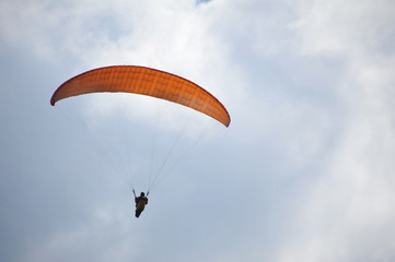 Paraglider flying on colored parachute in blue clear sky at a bright sunny summer day. Active lifestyle, extreme hobbies